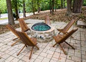 Thumbnail 10 of 20 - a stone fire pit with wooden chairs around it